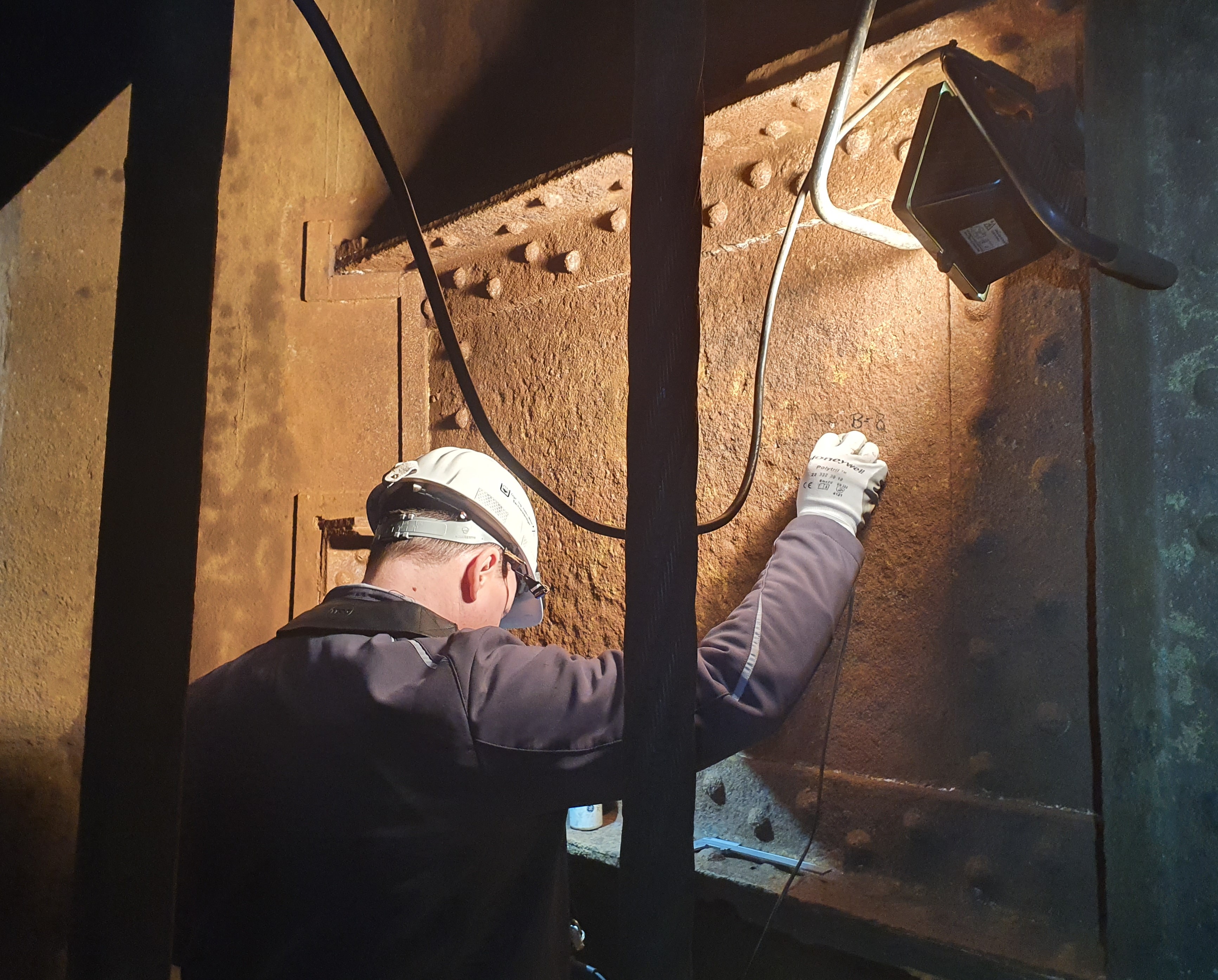 Ein Prüftechniker führt eine Ultraschallprüfung an einem Hauptträger im Schacht (Anlagenteil im Bergbau) durch.