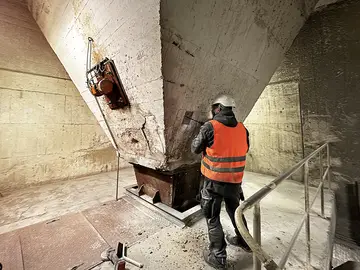 Ein Prüftechniker untersucht eine vorbereitete Prüffläche an einem Betonbauteil.